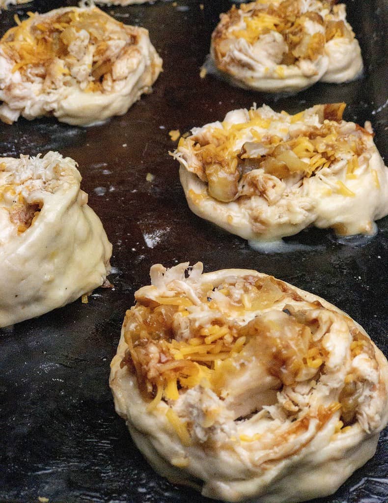 A sheet pan of unbaked barbecue chicken pizza pinwheels