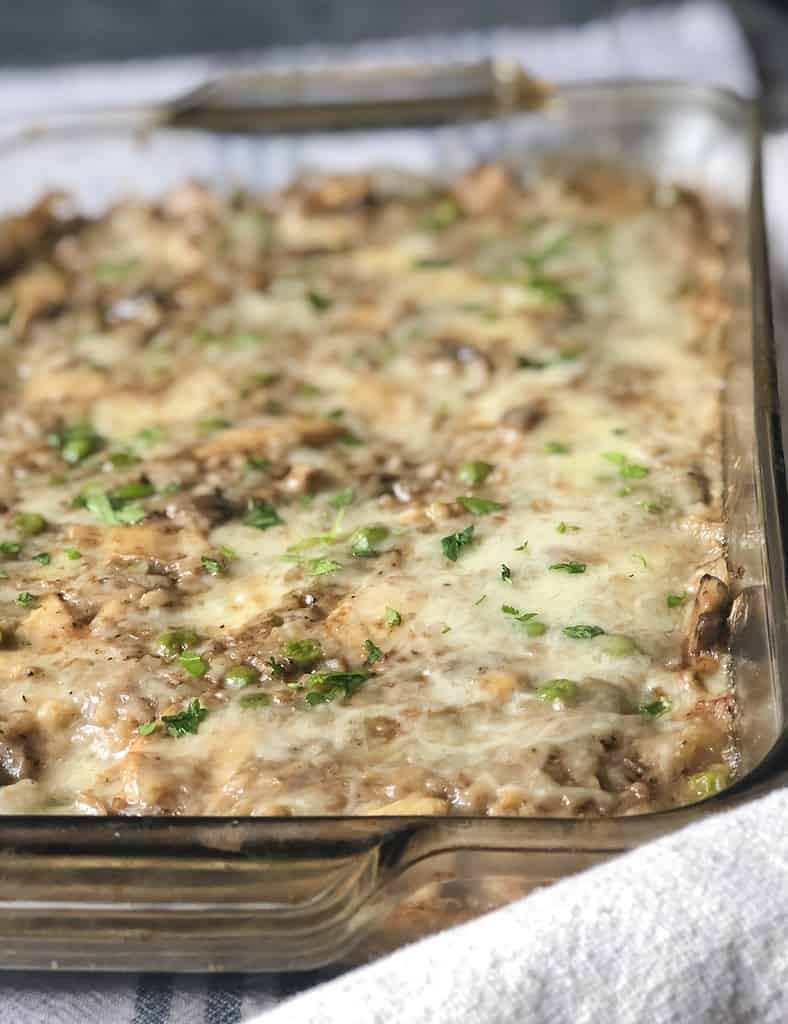 A rectangle casserole dish filled with cheesy cauliflower rice, mushrooms, peas and chicken. Made with a creamy balsamic sauce, Brie and Italian shredded cheese blend and baked until golden and bubbly.