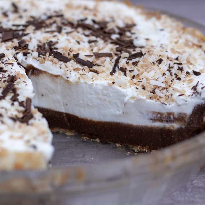 A whole chocolate coconut cream pie with a slice taken out. You can see the creamy homemade chocolate filling inside that’s topped with whipped cream and toasted coconut