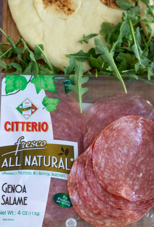 A package of Citterio genoa salalmi. A couple of slices of salami are on top of the package and there's a handful of arugula and a nann flatbread in the background.