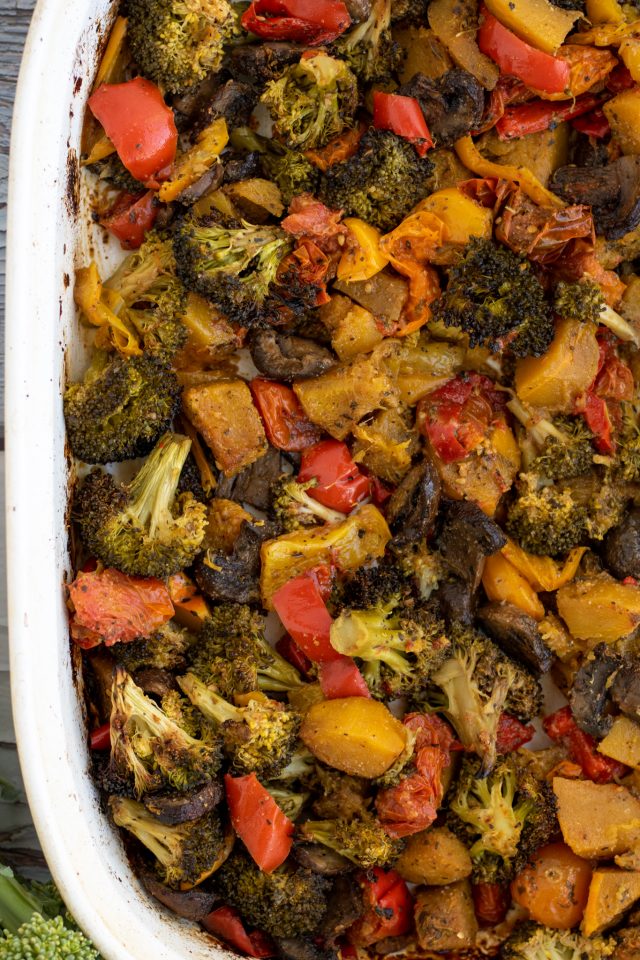 A rectangle white baking dish filled with roasted vegetables like broccoli, mushrooms and bell peppers