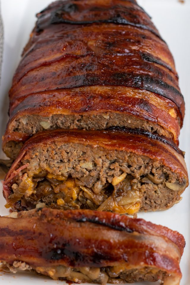 A loaf of meatloaf wrapped in bacon and stuffed with mushrooms, onions and cheddar cheese.