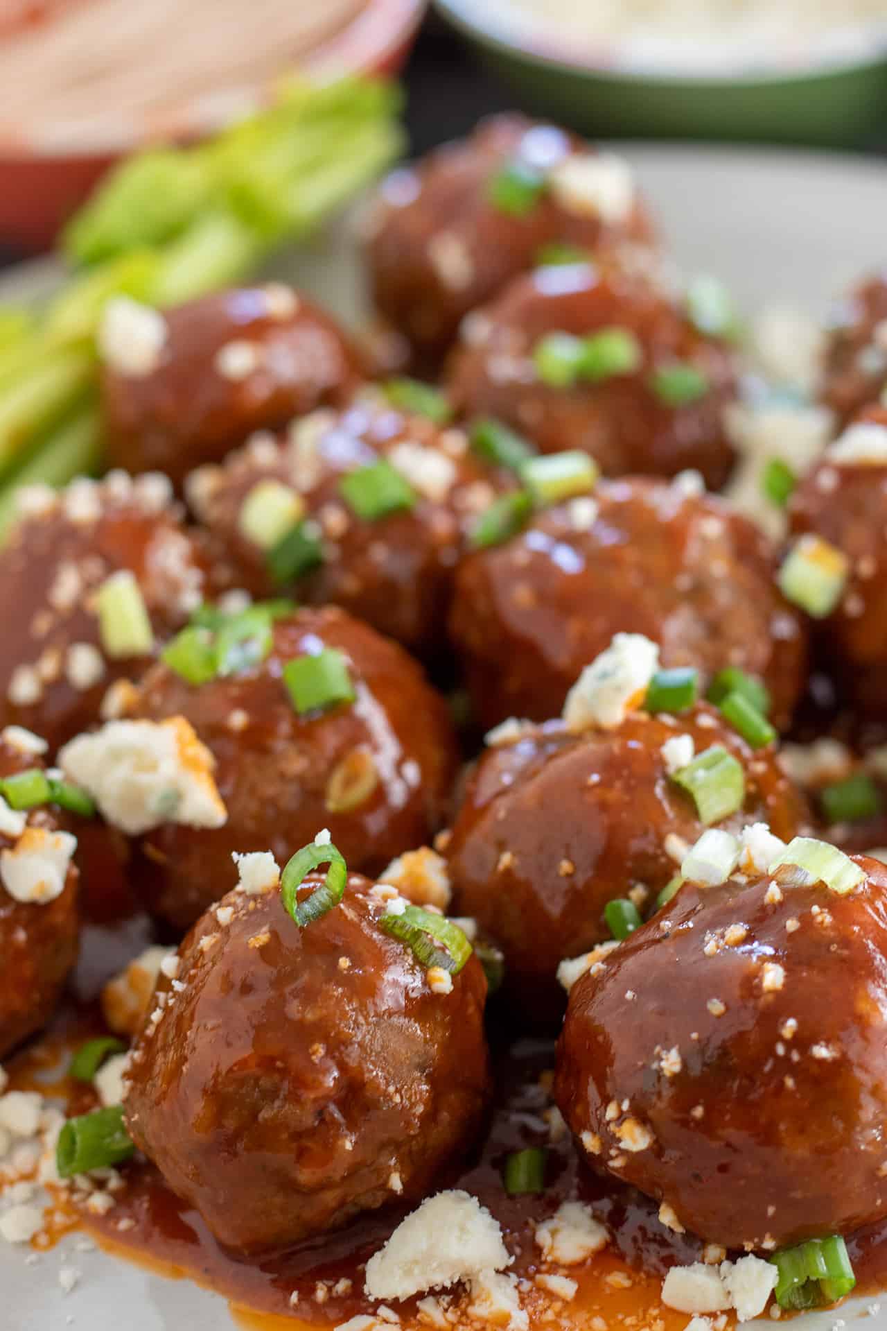 Chicken meatballs covered in a buffalo bbq sauce. They're topped with green onions and blue cheese crumbles.